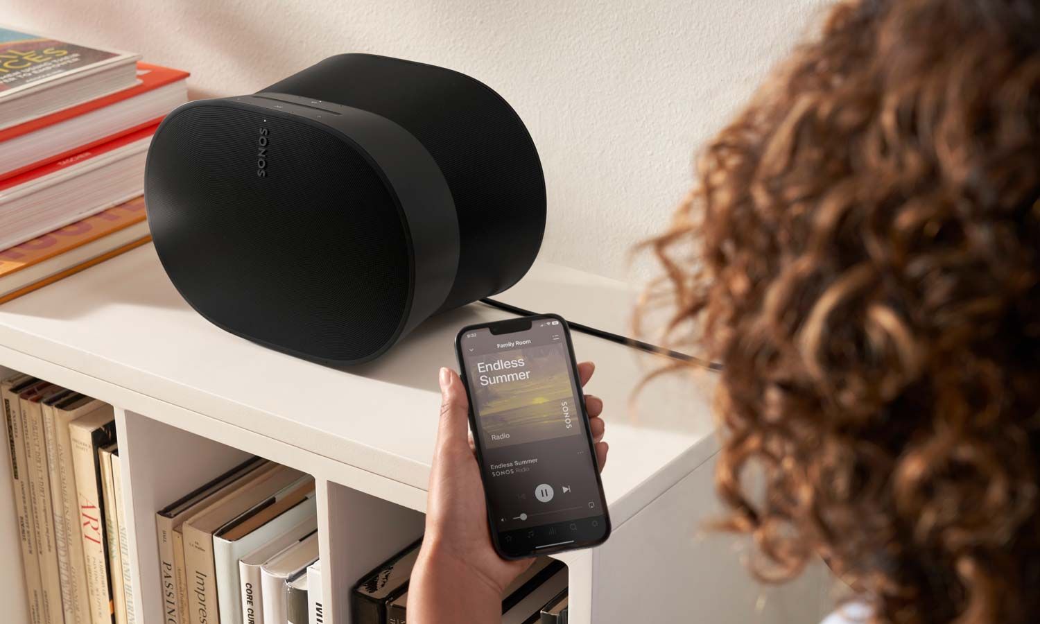 woman looking at a phone in front of a sonos speaker